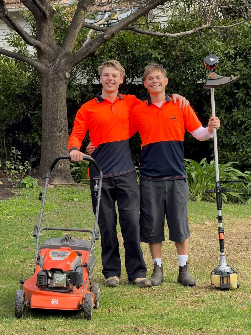 Brothers Hamish and Henry of HP Gardening standing on a lawn with their mower and line trimmer