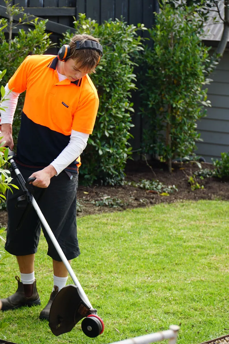 Henry trimming a lawn edge with a line trimmer