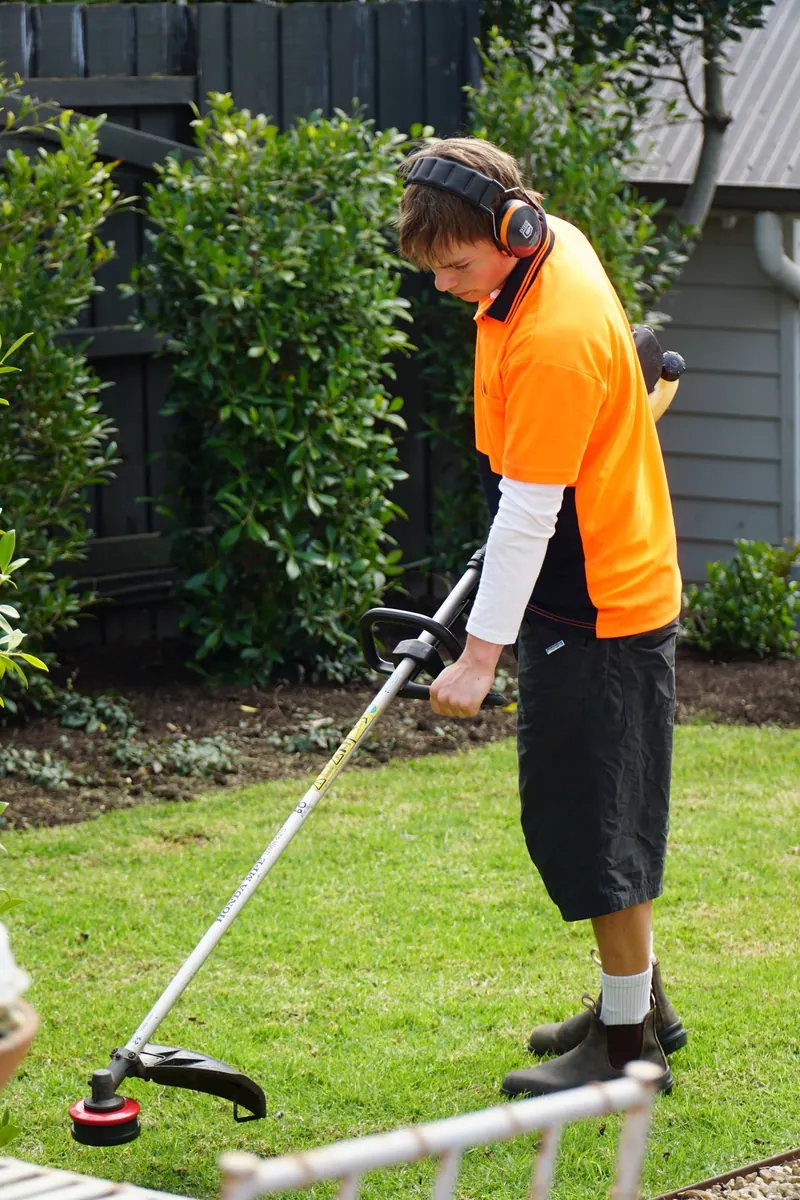 Henry trimming along a lawn edge with a line trimmer