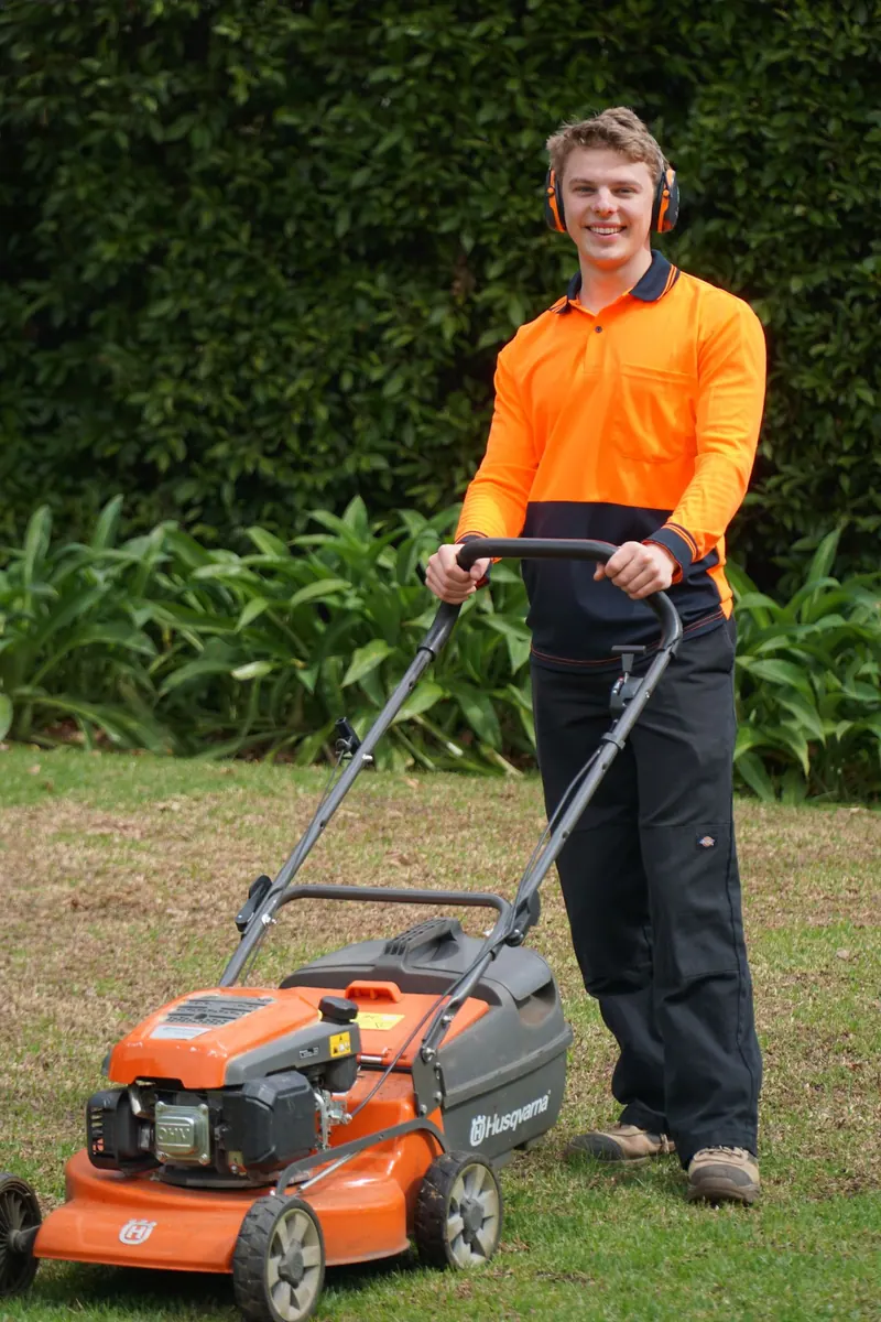 Hamish of HP Gardening smiling behind a lawn mower