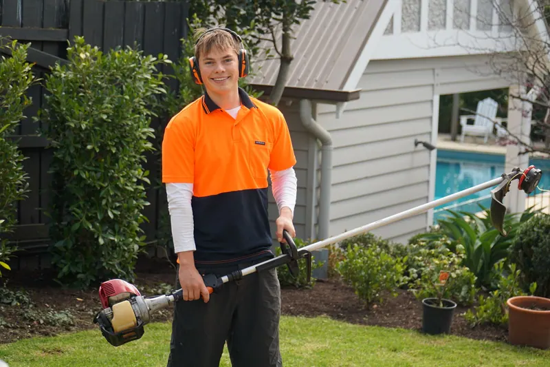 Henry standing in a garden holding a line trimmer